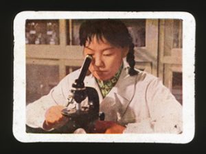 Slide depicting a female scientist looking into a microscope