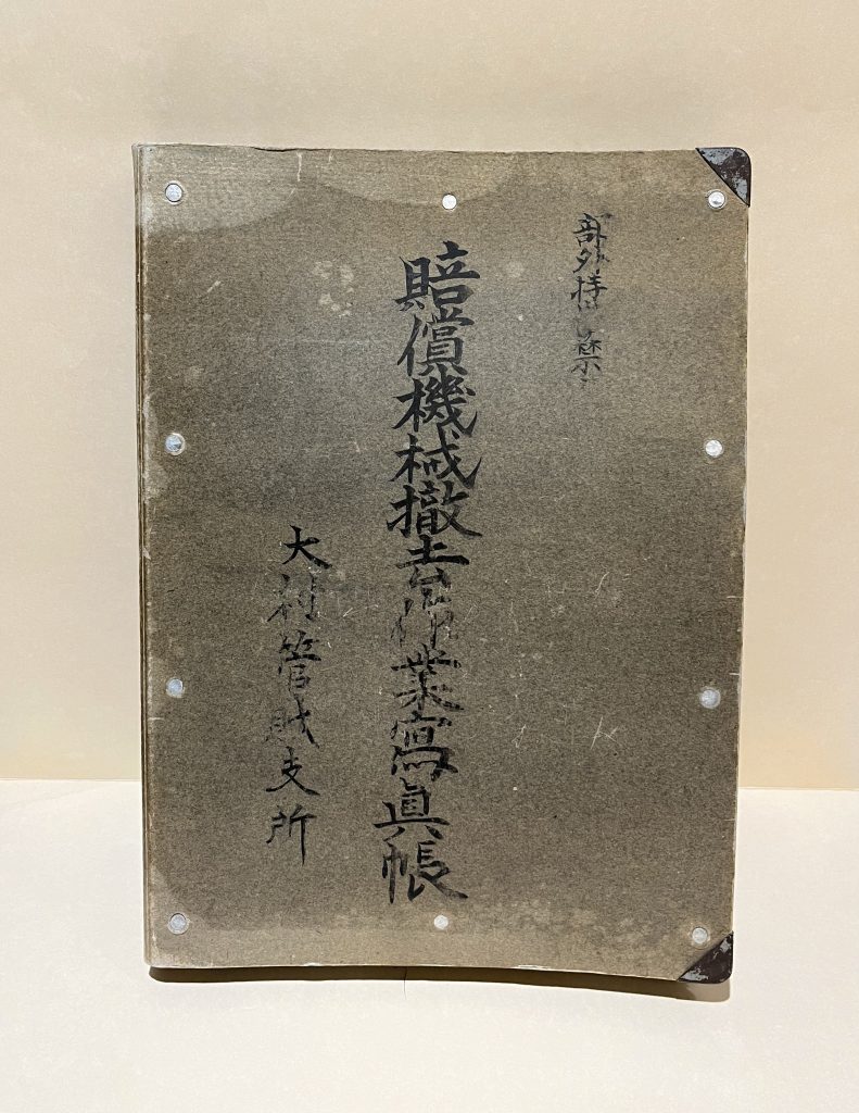 Cover of the photo album, with Japanese Kanji handwritten on it. Text reads: 賠償機械撤去作業寫真帳. 大村管械支所