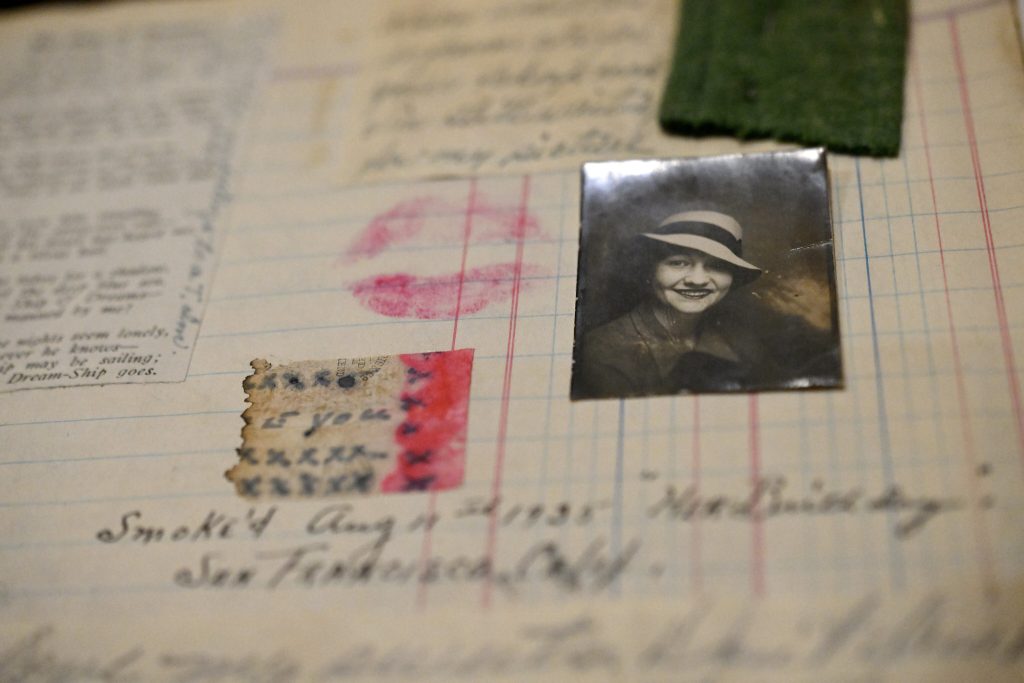 Page from a 1930s scrapbook kept by a sailor. Scrapbook shows a photograph of a woman, used cigarette paper, and a lipstick kiss.